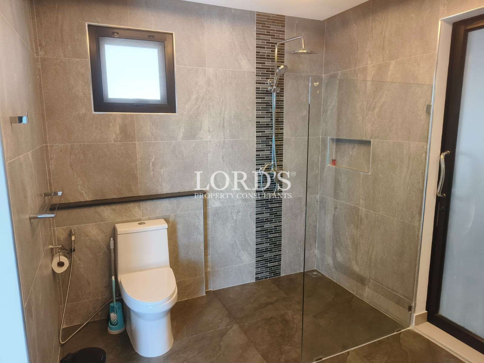 Contemporary bathroom with glass-enclosed shower and tiled accent wall.