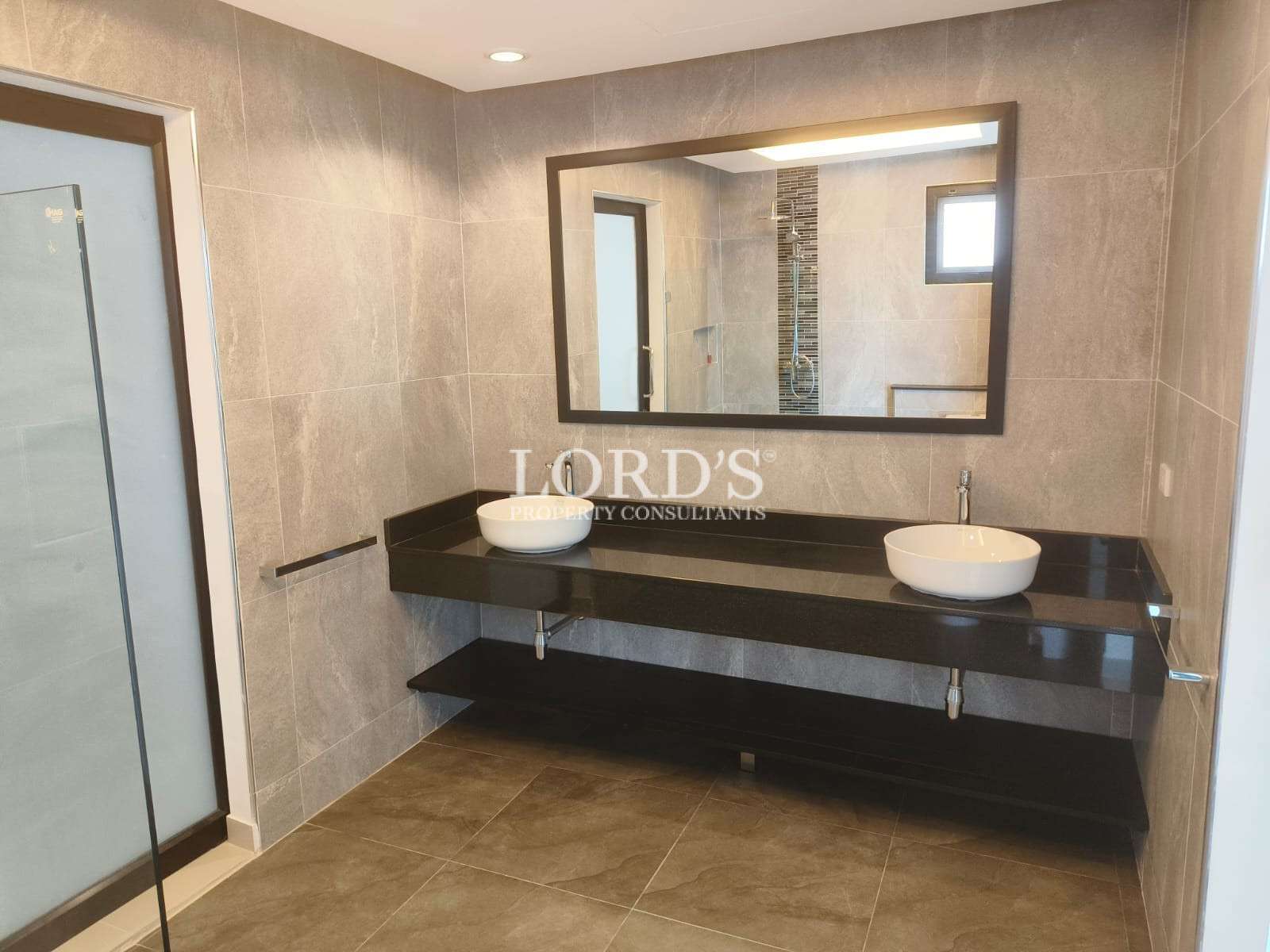 Modern bathroom with double vessel sinks, large wall mirror, and dark floating vanity.