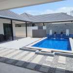 Modern courtyard with rectangular swimming pool, waterfall feature wall, and covered outdoor seating area.