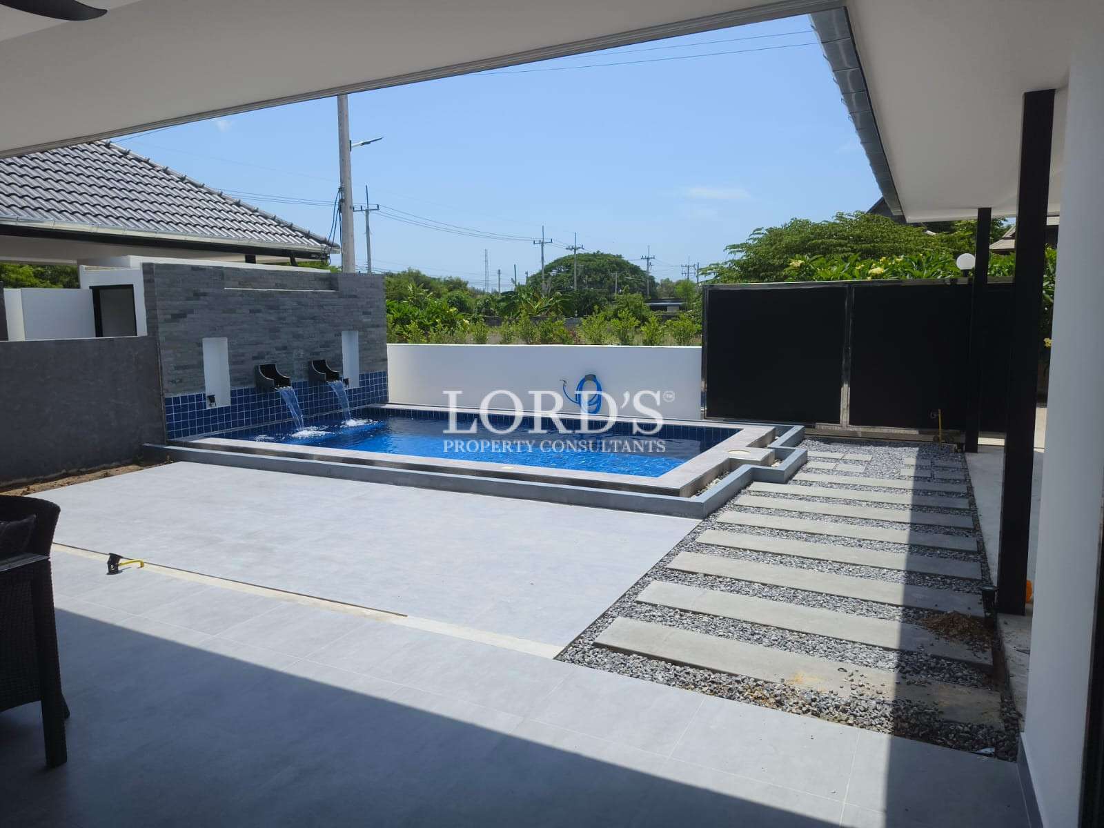 Modern backyard with a small private swimming pool, water features, tiled patio, and sliding gate.
