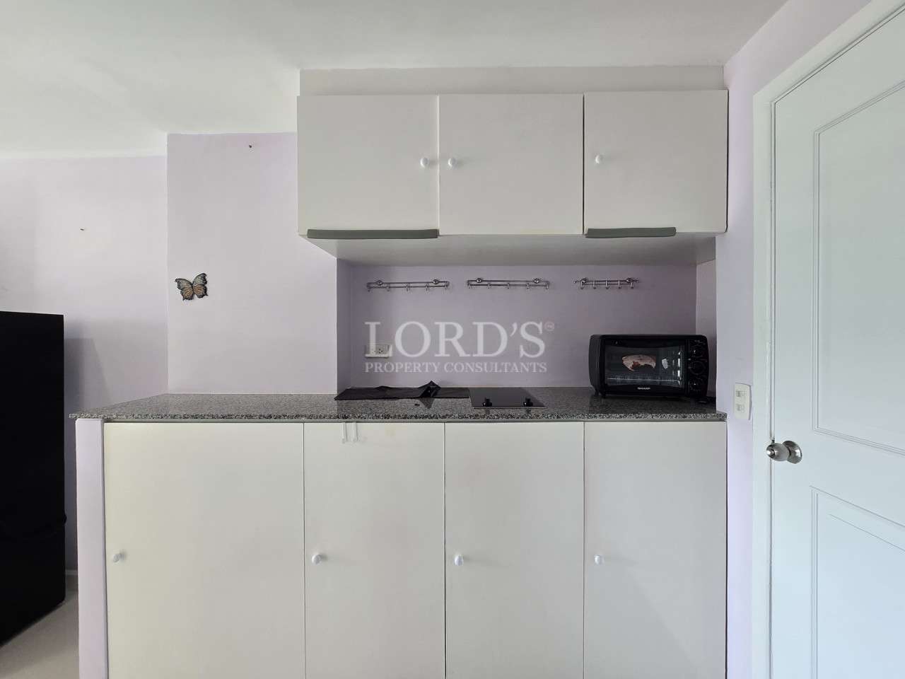 Compact kitchenette with white cabinets and countertop workspace.