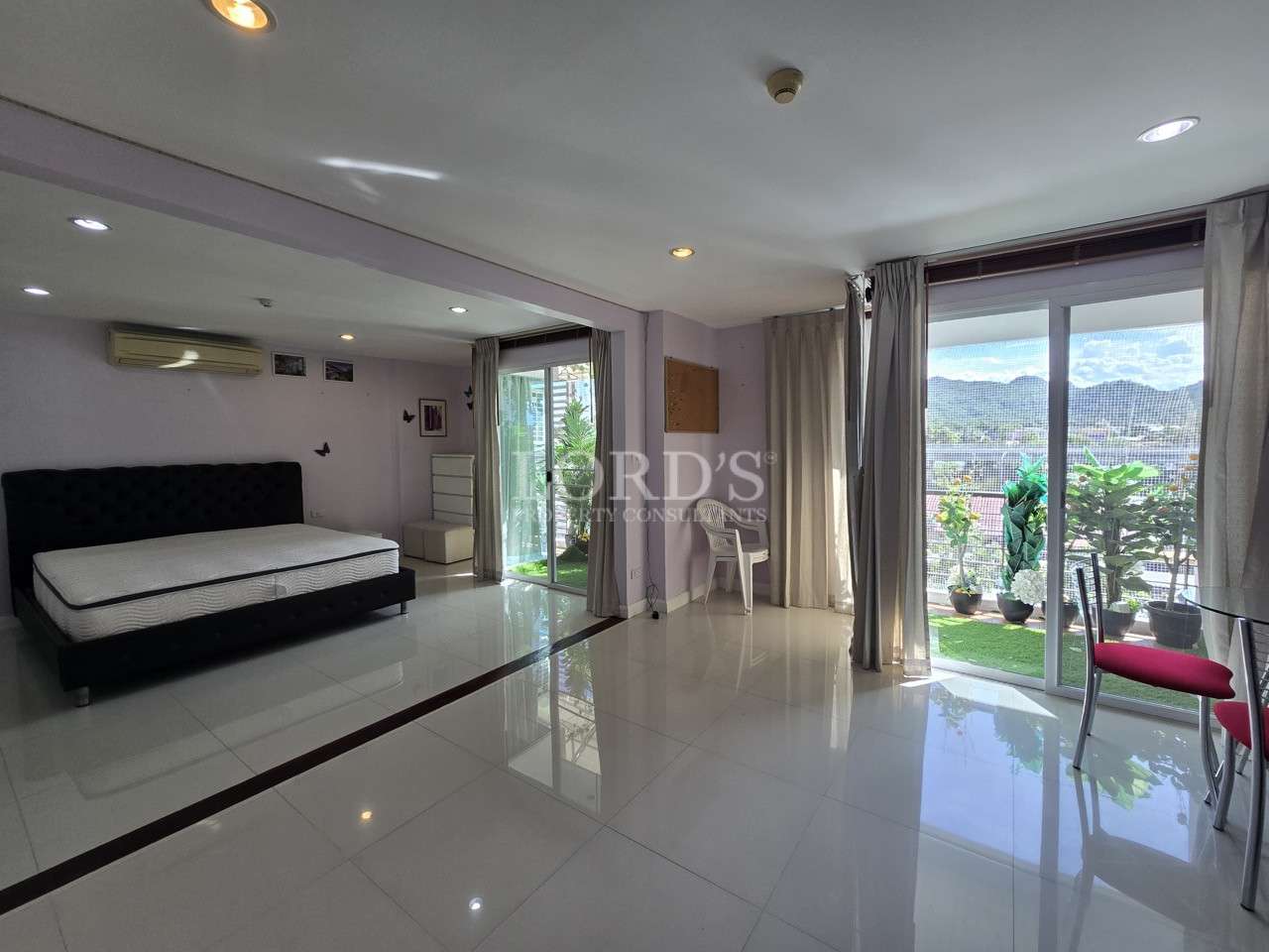 Large open bedroom with balcony access and mountain views.