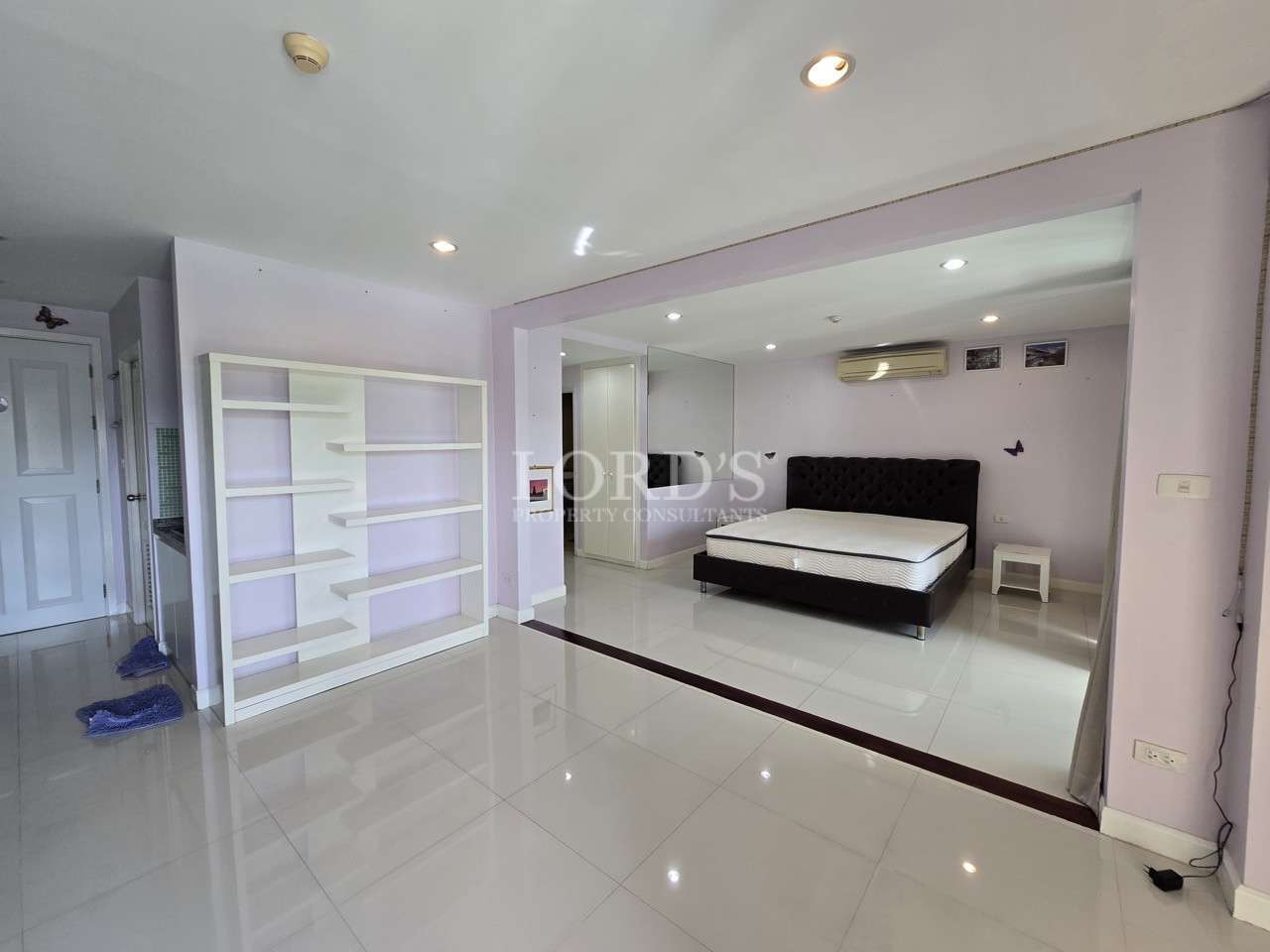 Spacious bedroom with open layout and built-in shelving.
