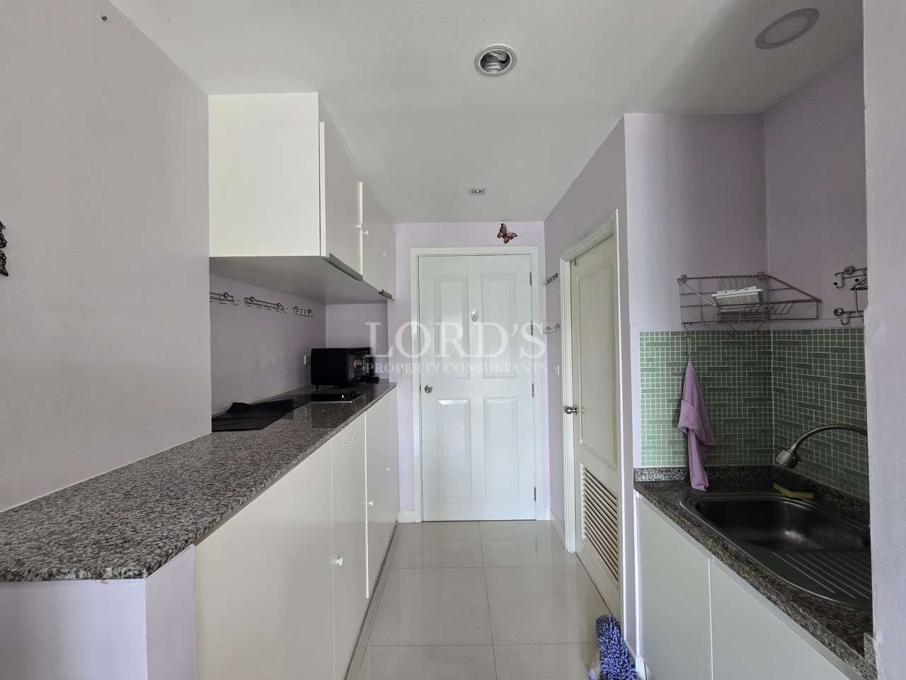 Compact utility kitchen with cabinets, countertop workspace, and sink area.