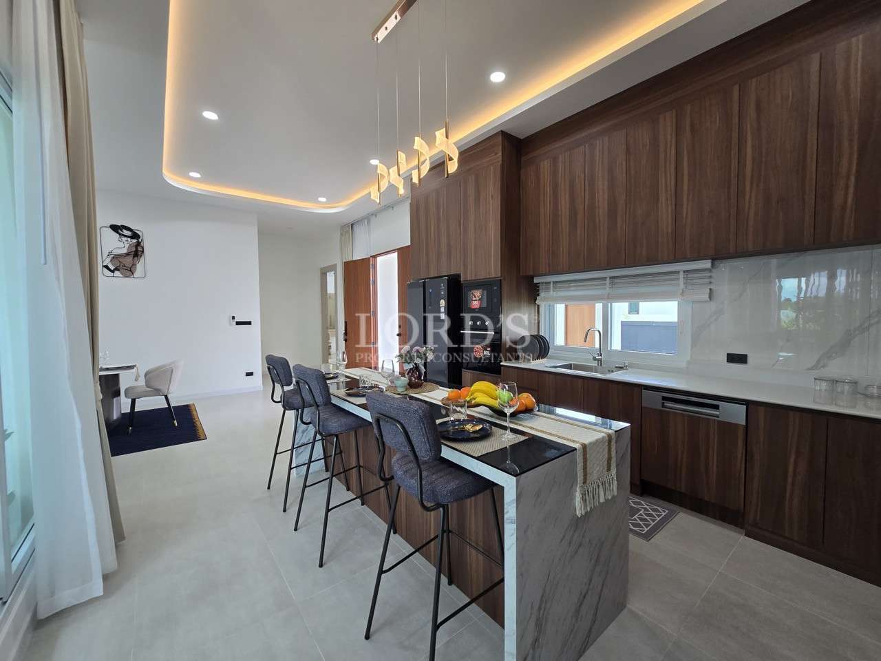 Contemporary kitchen with wood cabinetry, marble island seating, pendant lights, and black appliances.