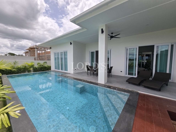 Modern white house with covered patio and rectangular swimming pool with built-in steps.