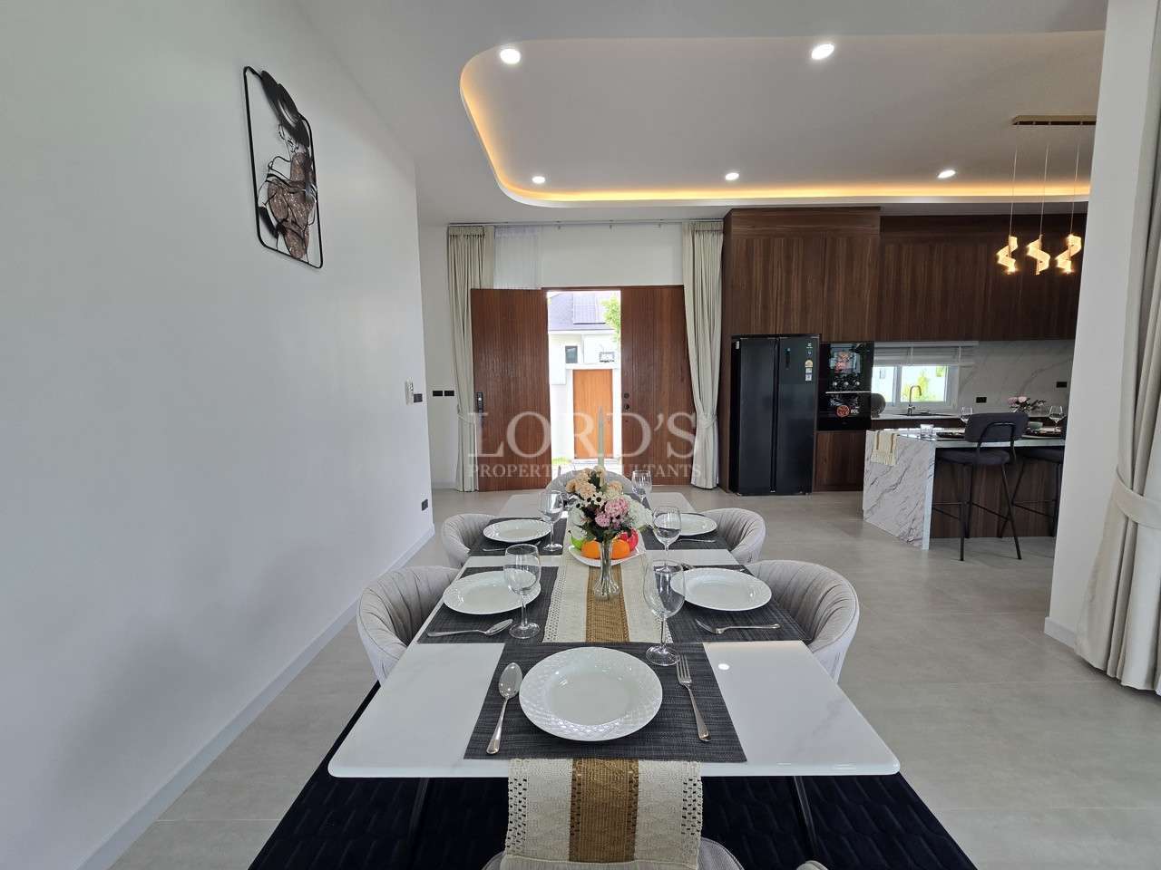 Modern dining table set for four with open kitchen and wood cabinetry in the background.