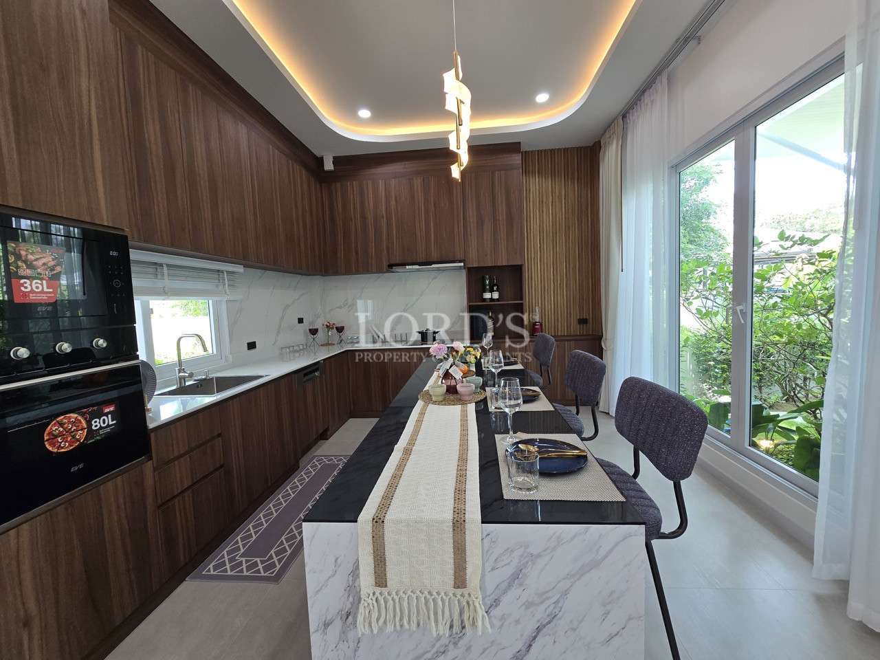 Modern kitchen with dark wood cabinets, marble island dining table, and large sliding glass doors.