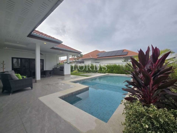 Modern backyard with swimming pool, covered patio seating, and landscaped garden.