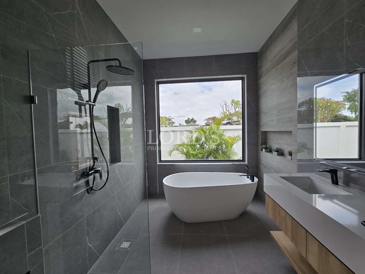 Modern bathroom with walk-in glass shower, freestanding bathtub, and large window.