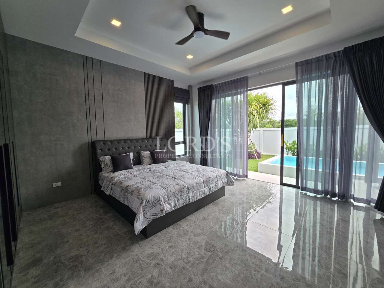 Modern bedroom with sliding glass doors opening to a private pool and garden.