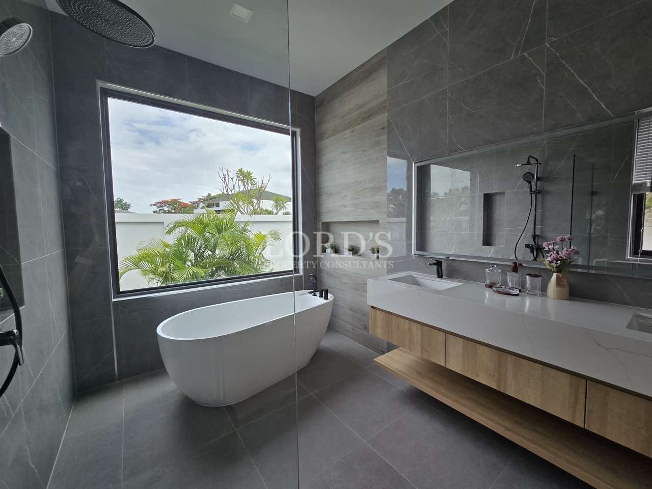 Modern bathroom with freestanding bathtub, large window, and floating double vanity.