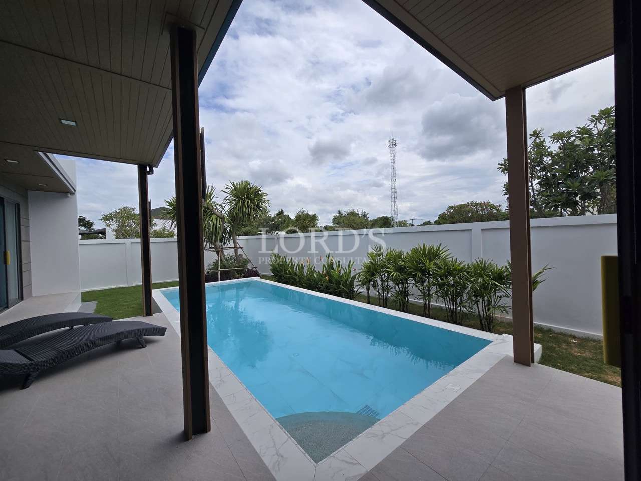 Private rectangular swimming pool viewed from a covered patio with lounge chairs.