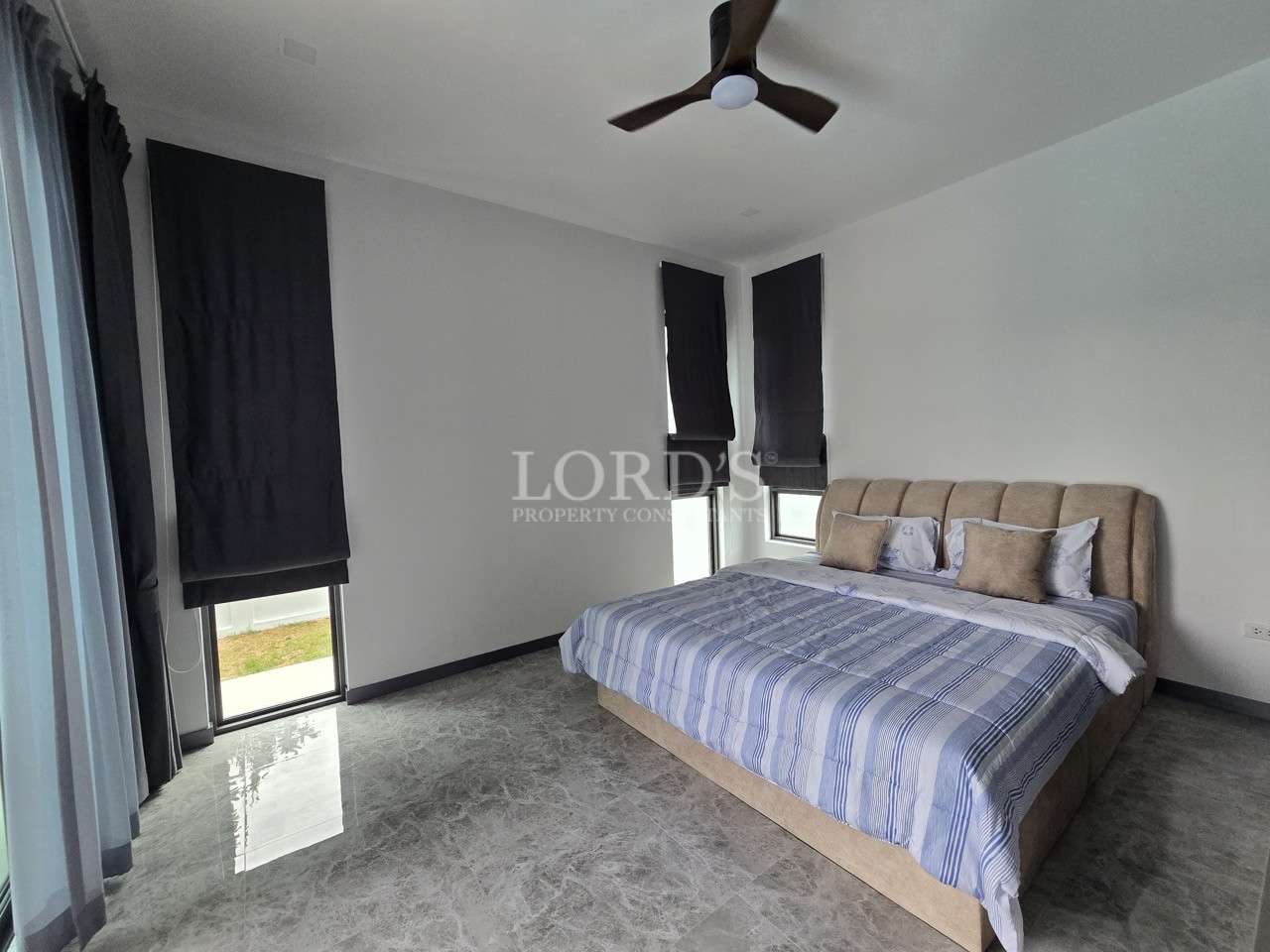 Modern minimalist bedroom with upholstered bed, marble floor, and dark window blinds.