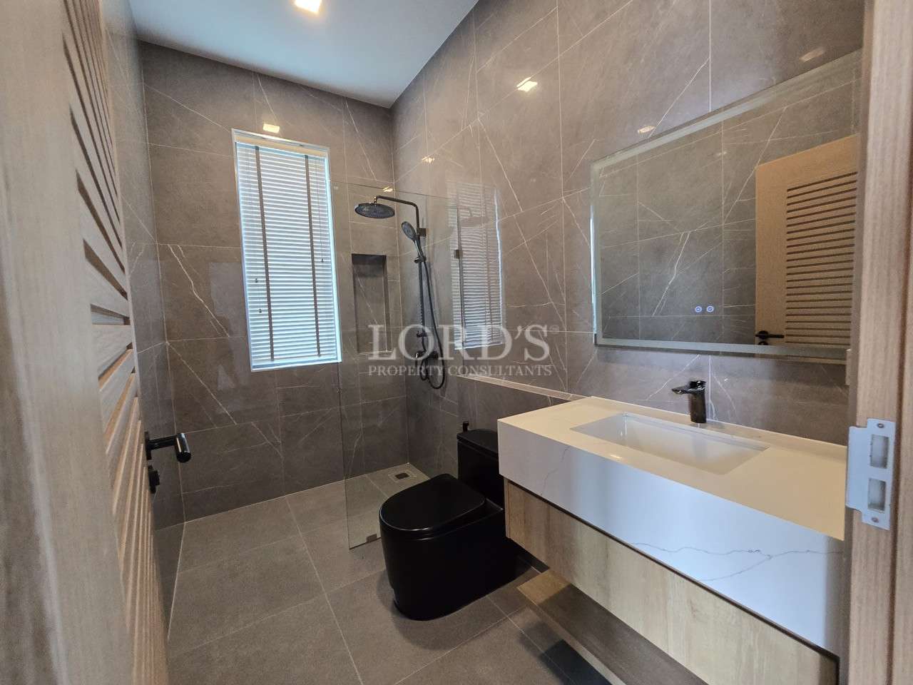 Modern bathroom with walk-in glass shower, black toilet, and floating white vanity.