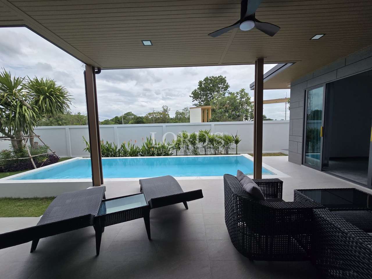 Covered patio with outdoor lounge chairs overlooking a private swimming pool.