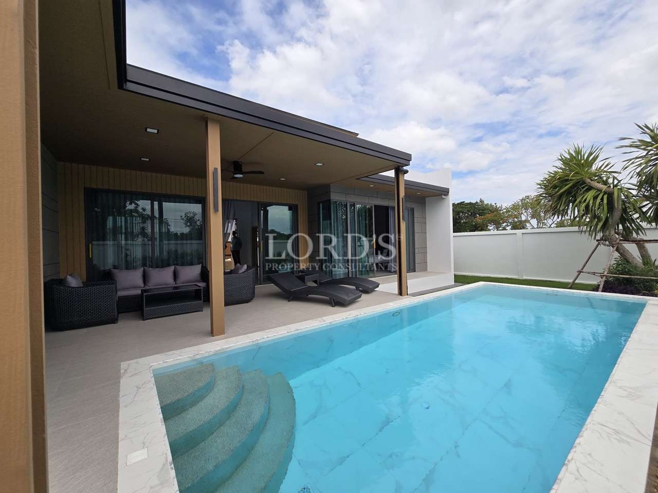 Modern villa patio with private swimming pool, lounge chairs, and covered outdoor seating area.