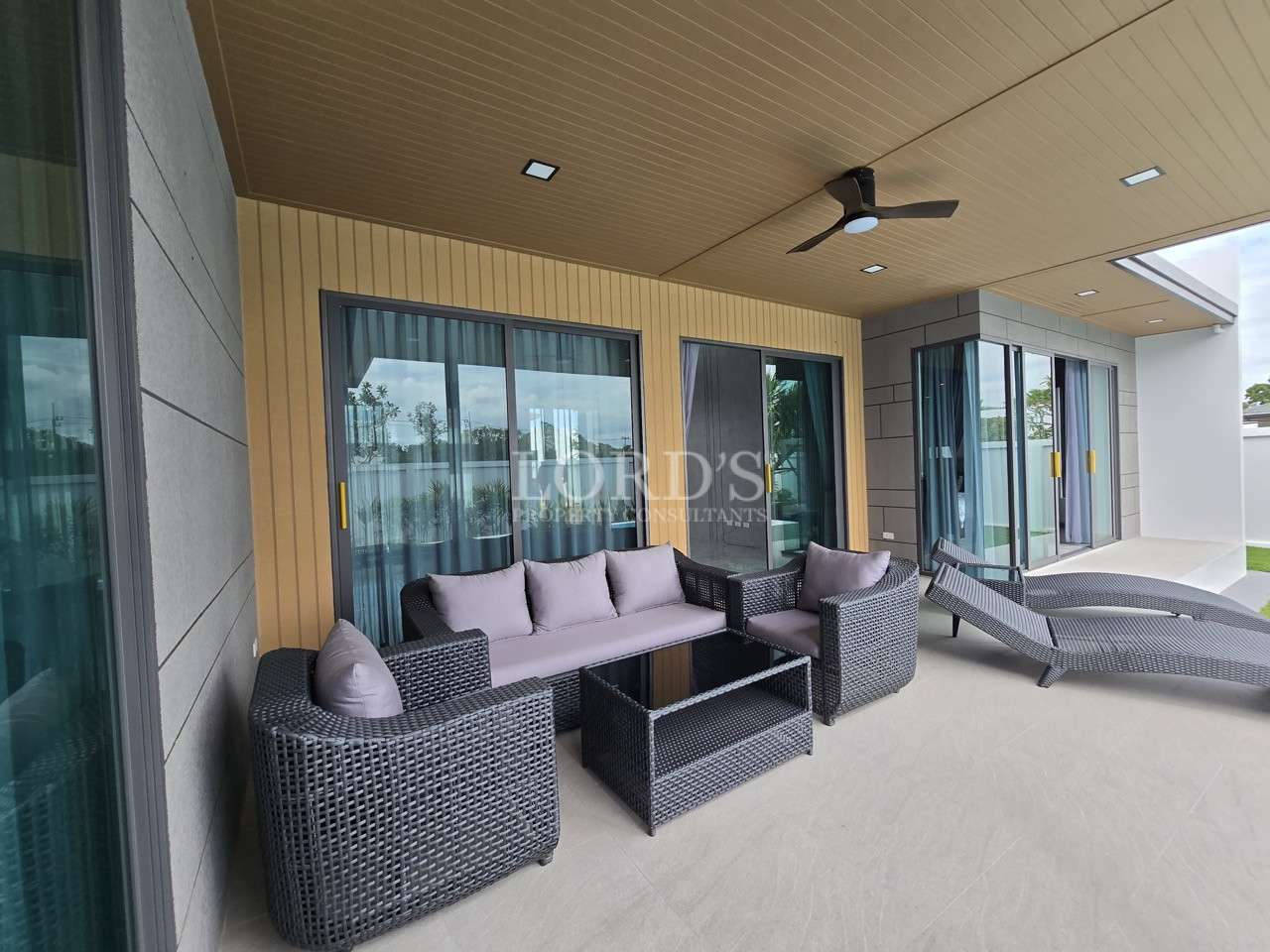 Outdoor terrace with seating area and sun loungers at a modern villa