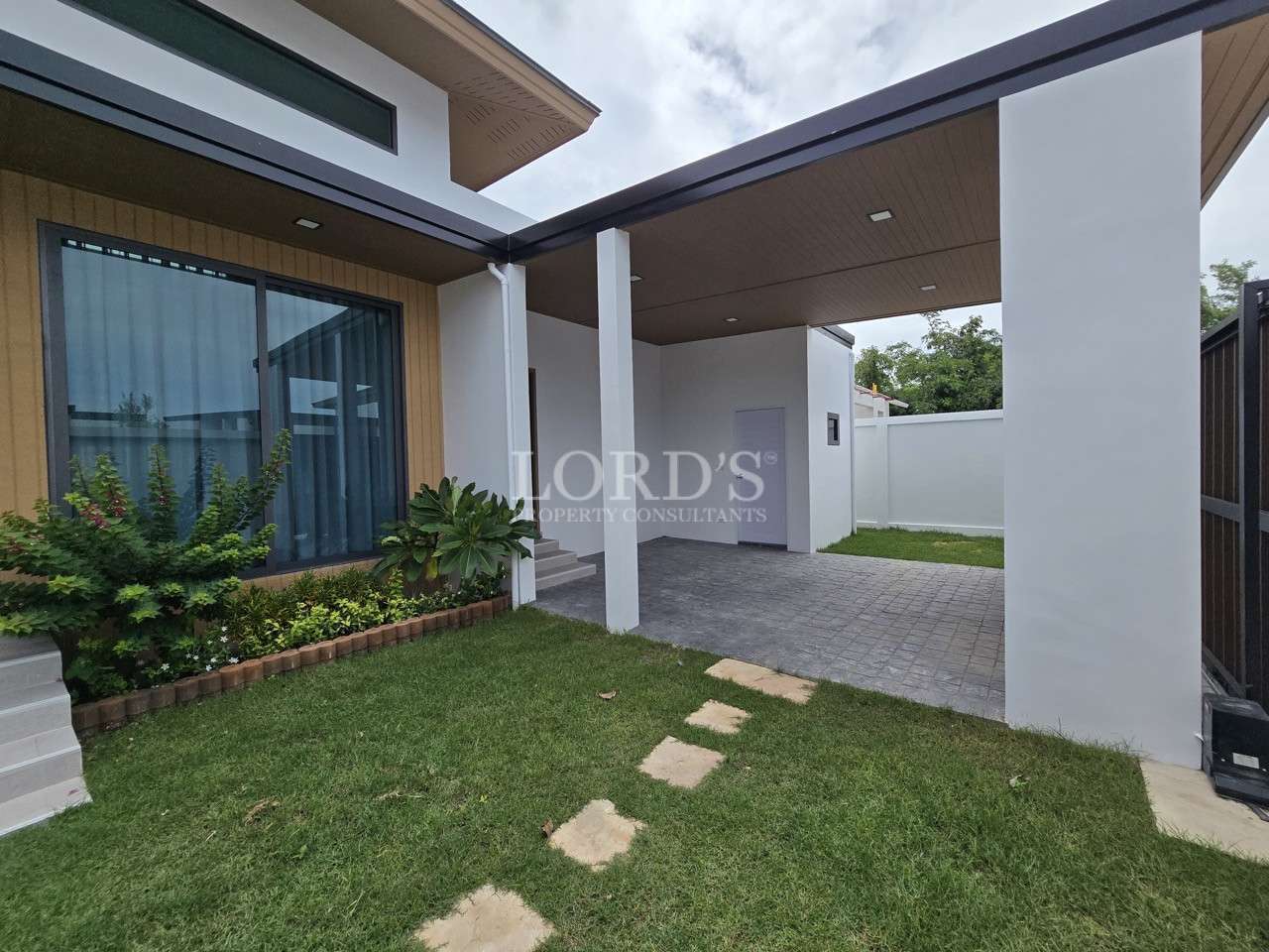 Modern villa exterior with covered carport, garden lawn, and large windows