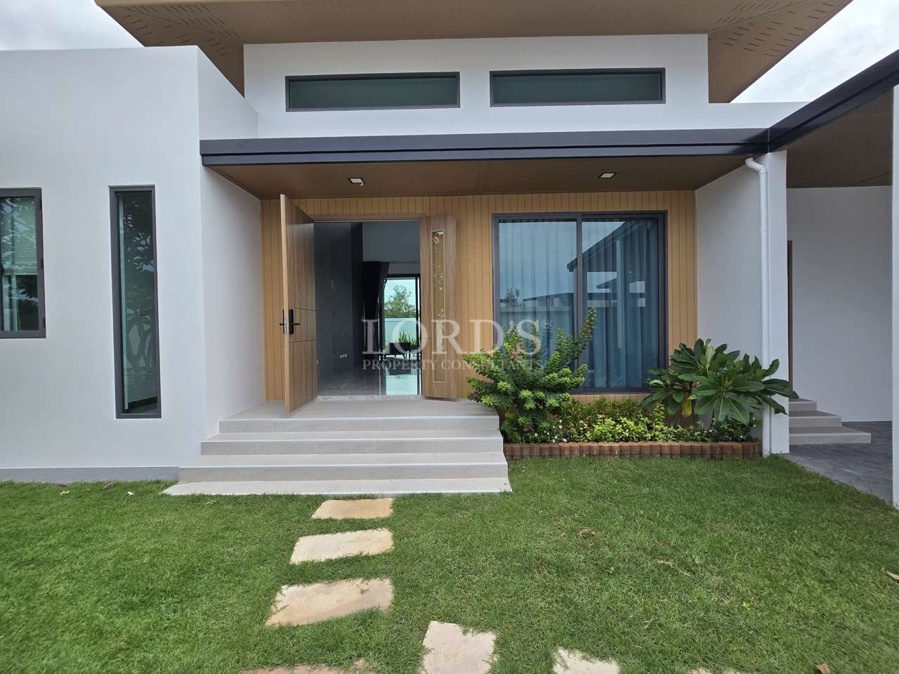 Modern single-story villa exterior with front garden and entrance steps