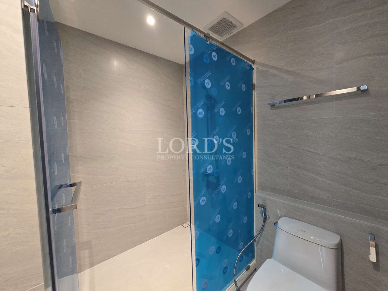 Modern bathroom with walk-in glass shower, toilet, and neutral tile walls