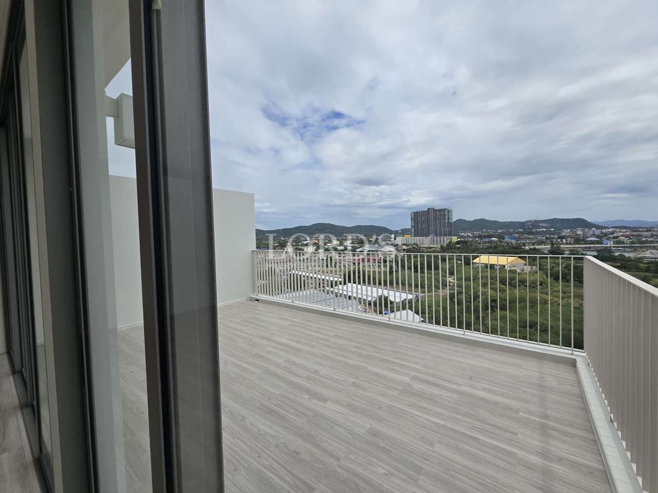 Spacious apartment balcony with city and mountain views.