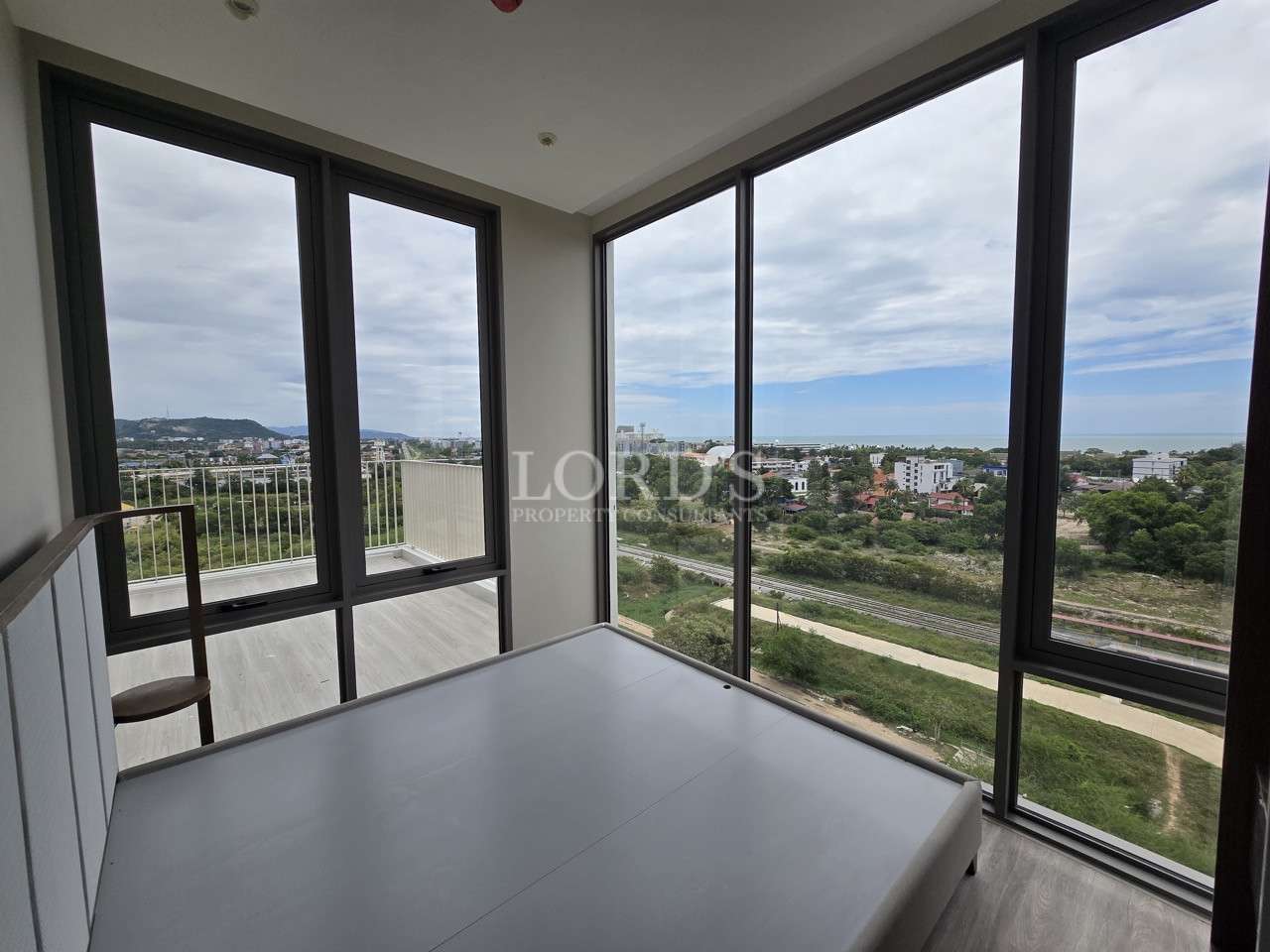 Bedroom with floor-to-ceiling windows and panoramic city and sea views.