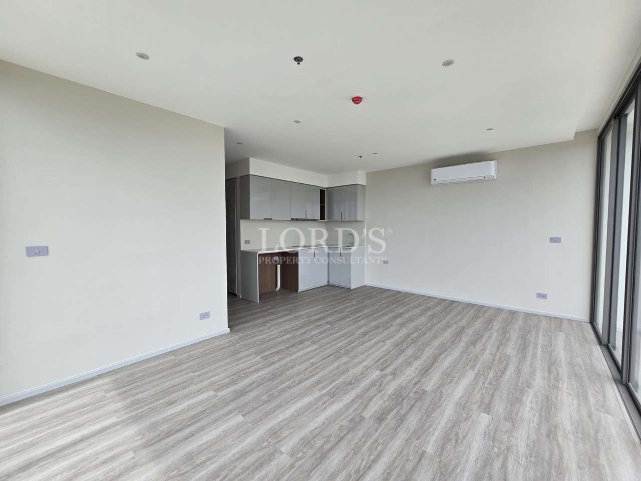 Spacious modern apartment living area with open kitchen and wood-look flooring.