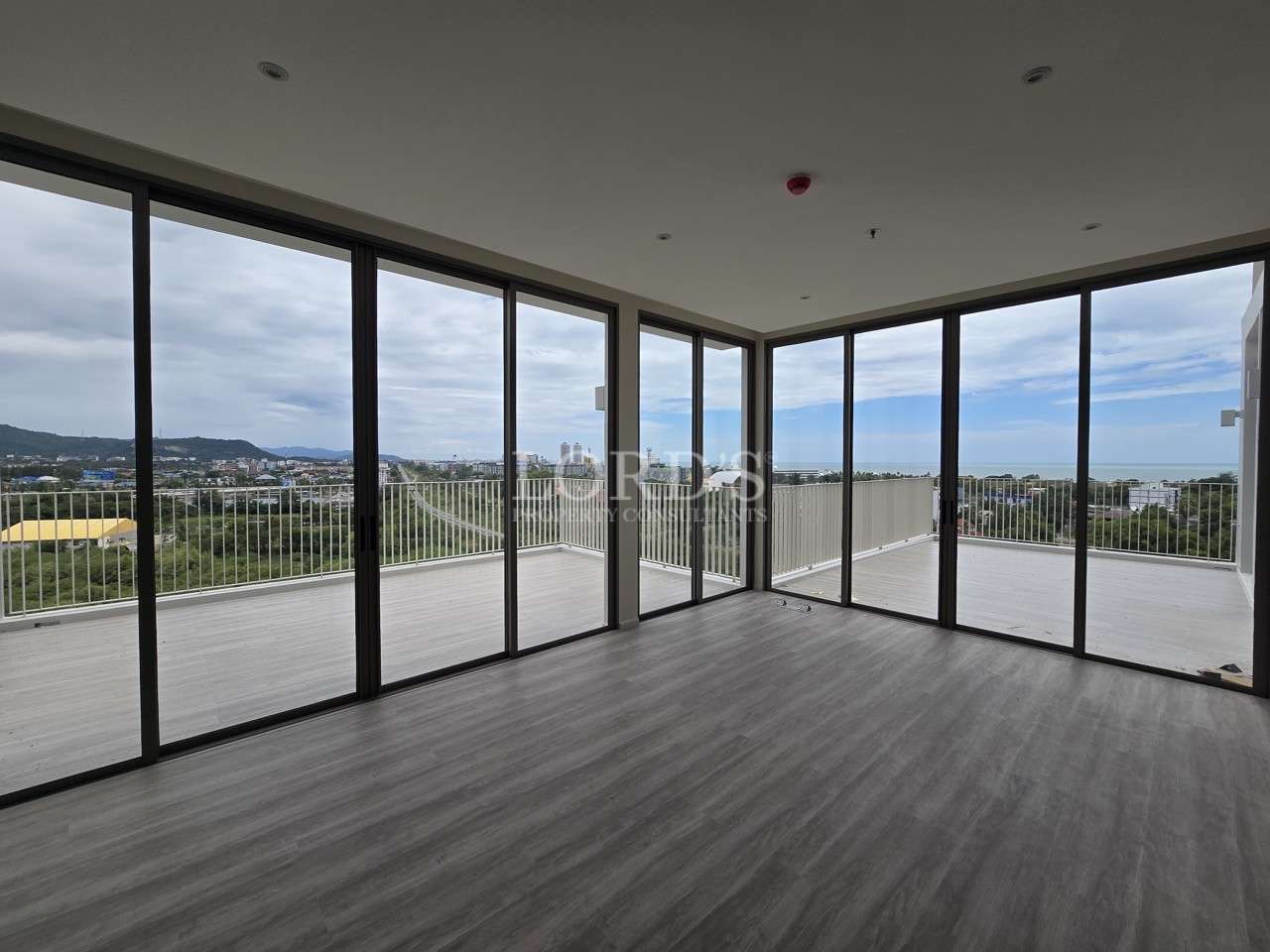 Corner living room with floor-to-ceiling glass doors and panoramic balcony view.