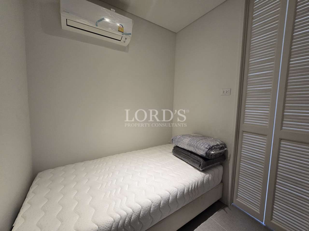 Small modern bedroom with single bed, air conditioning, and built-in wardrobe