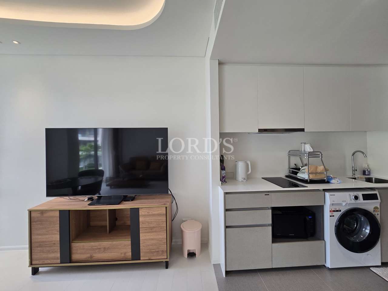 Modern condo living area with TV unit and compact open kitchen