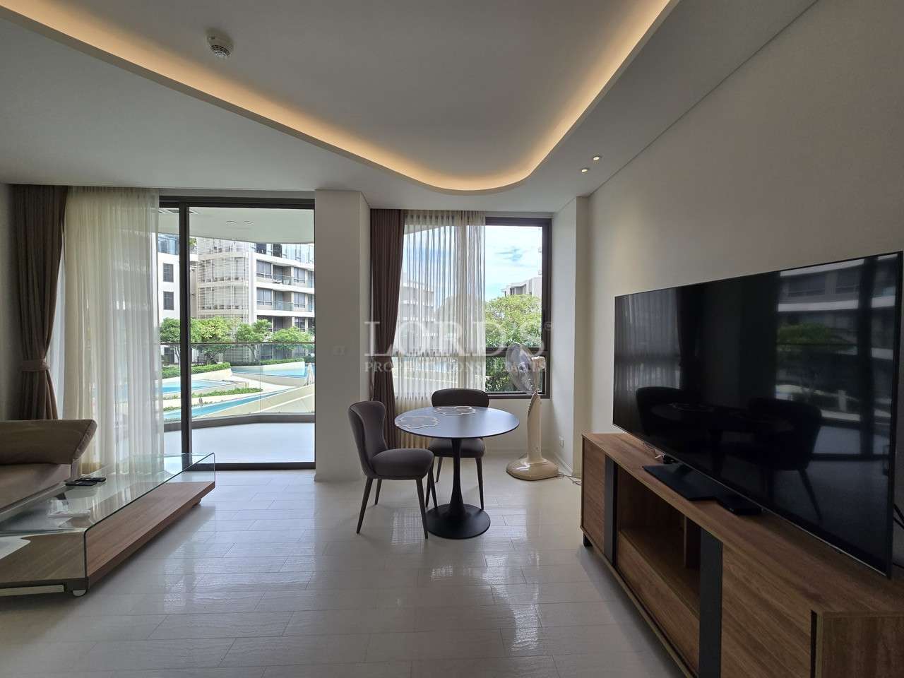 Modern condo living room with TV unit, dining table, and balcony access
