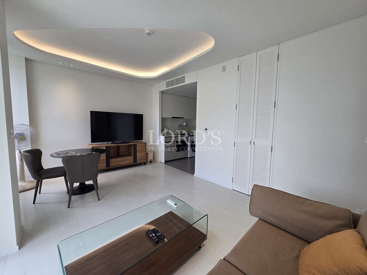 Modern condo living room with sofa, TV cabinet, dining table, and soft ceiling lighting