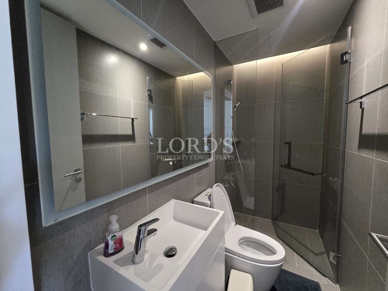 Modern bathroom with vanity sink, toilet, and glass-enclosed shower