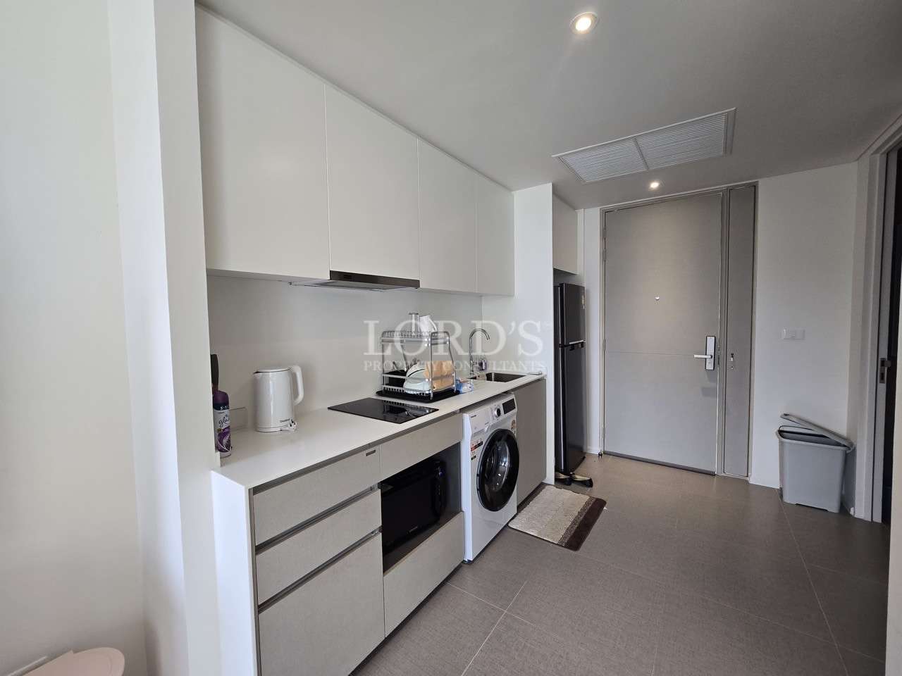 Modern compact kitchen with built-in cabinets, washing machine, and appliances