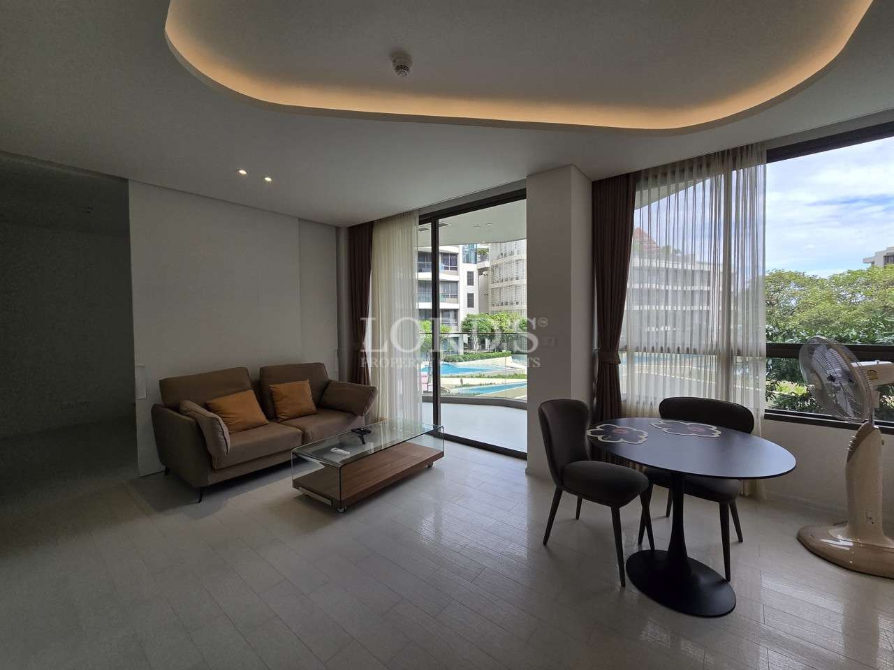 Modern furnished living room with dining area, large windows, and balcony access.