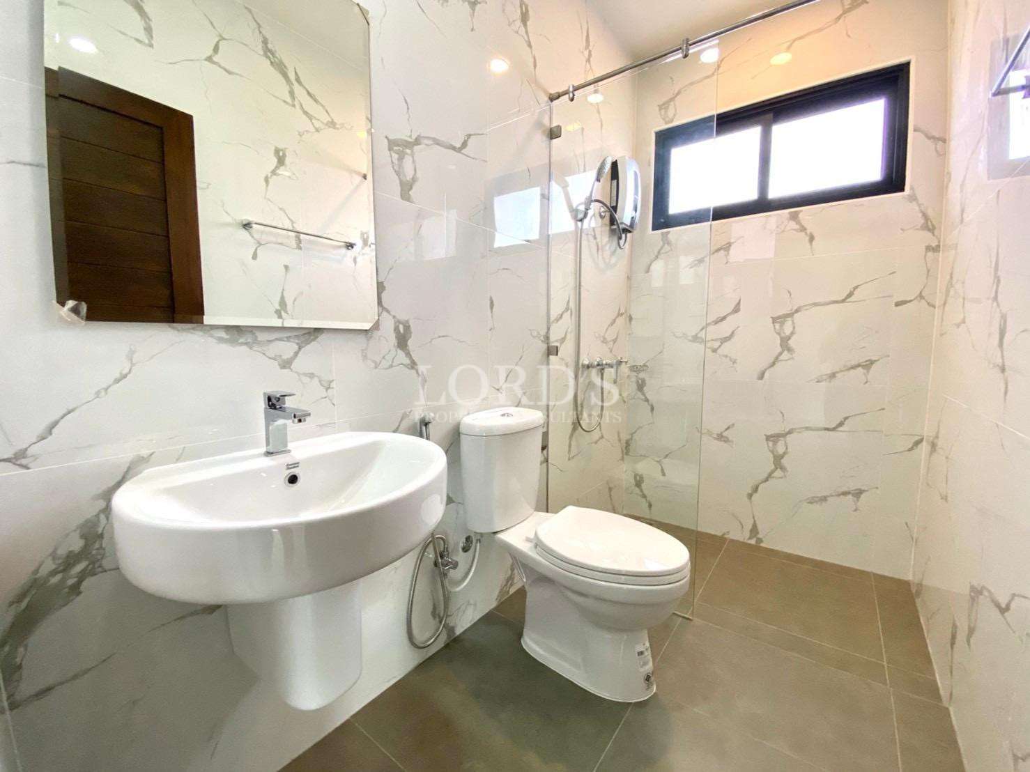 Modern bathroom with marble-look tiles, glass shower, and contemporary fixtures.