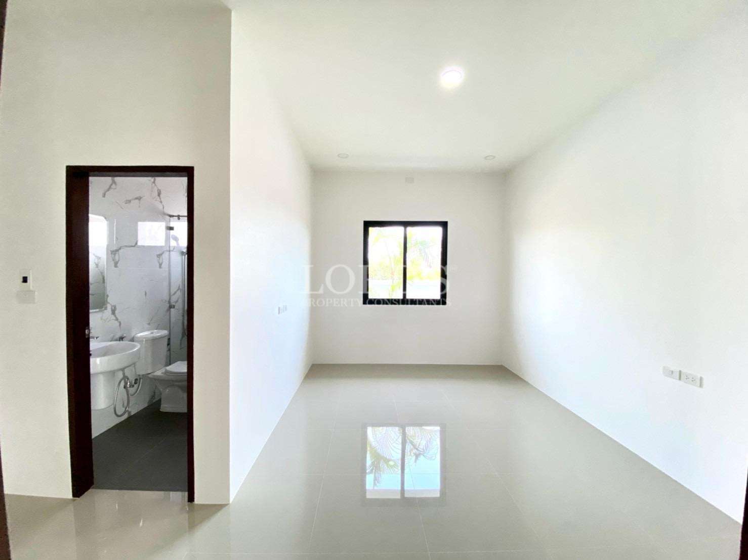 Modern bedroom with ensuite bathroom, glossy tiled floor, and window.