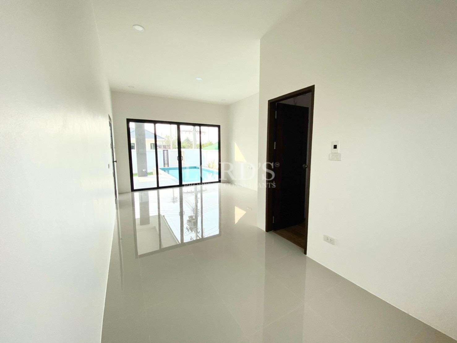 Modern living room with glossy tiled floor and sliding glass doors opening to pool.