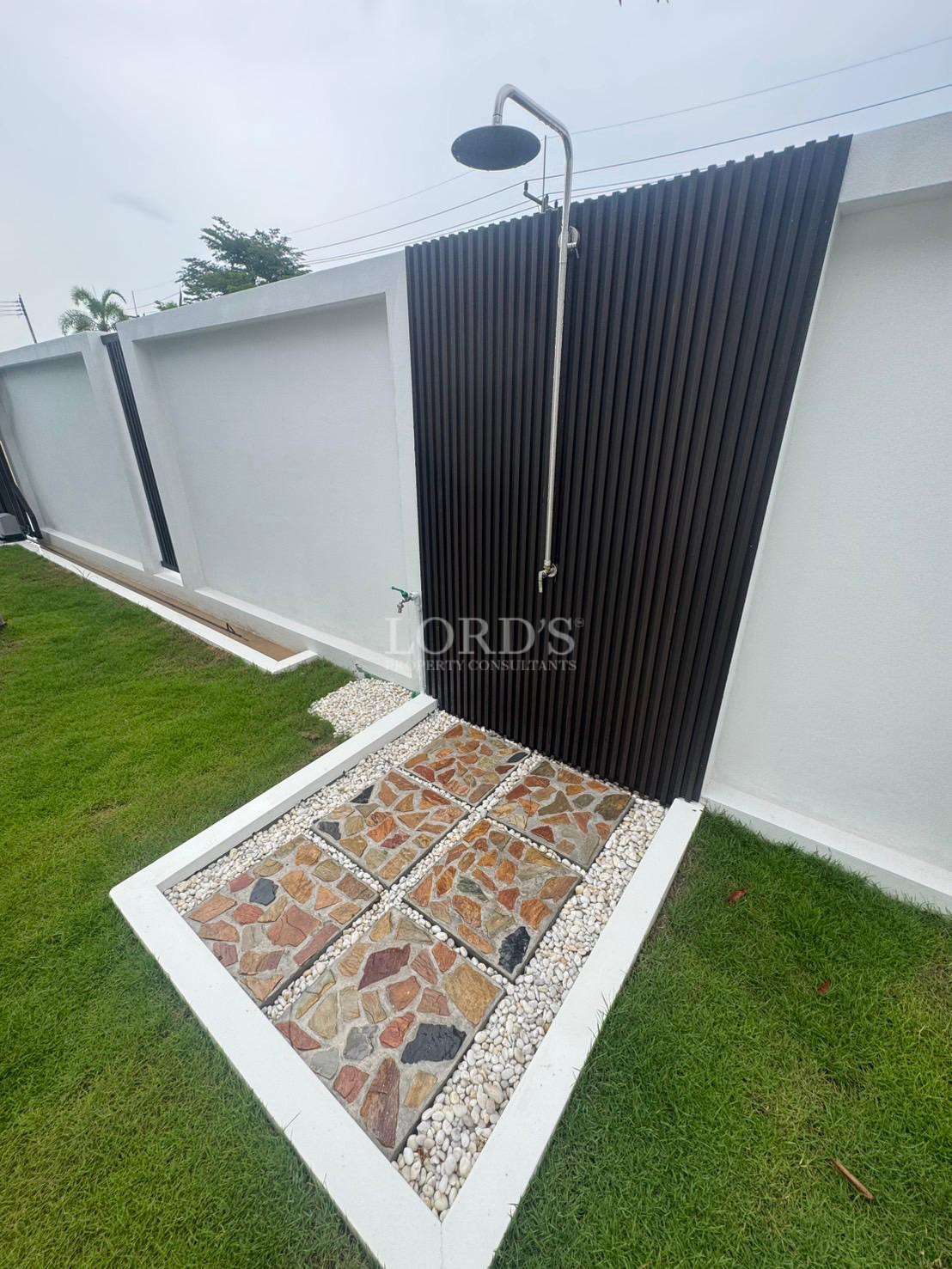 Outdoor garden shower with stone tile flooring and modern privacy wall