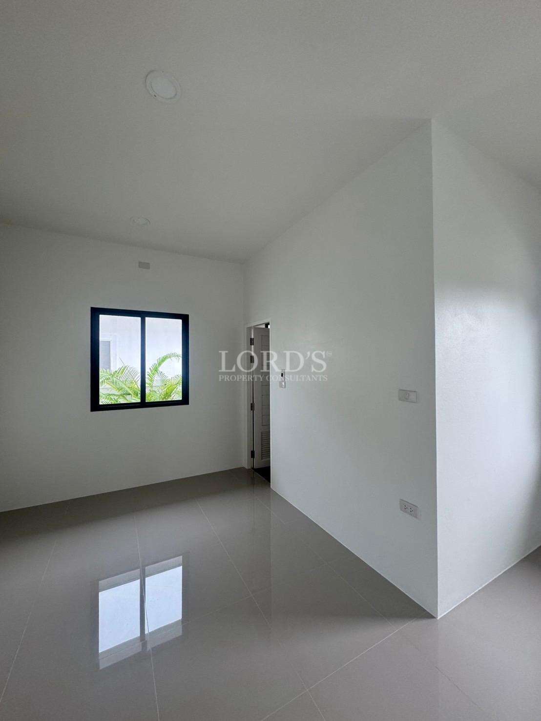 Empty modern bedroom with tiled floor, white walls, and window with natural light