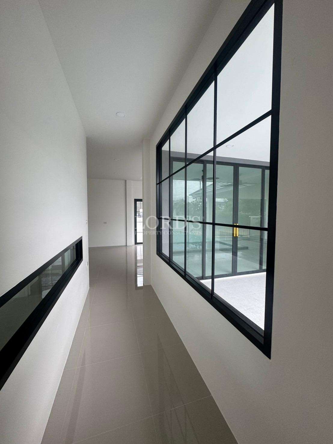 Modern hallway with large black-framed windows and glossy tiled floor
