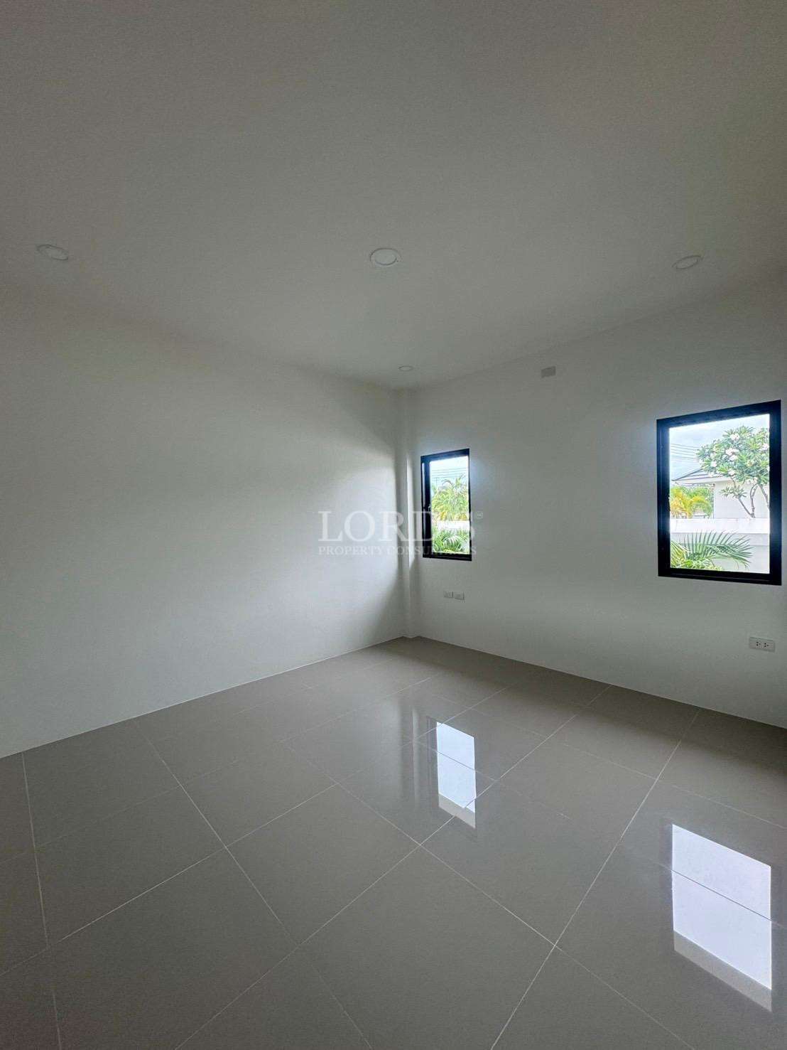Empty modern bedroom with tiled floor, white walls, and two windows