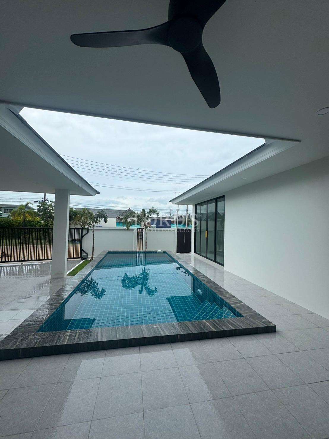 Private swimming pool viewed from covered terrace with ceiling fan
