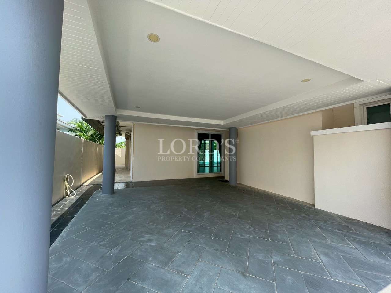 Covered carport with tiled floor and support columns in modern villa.