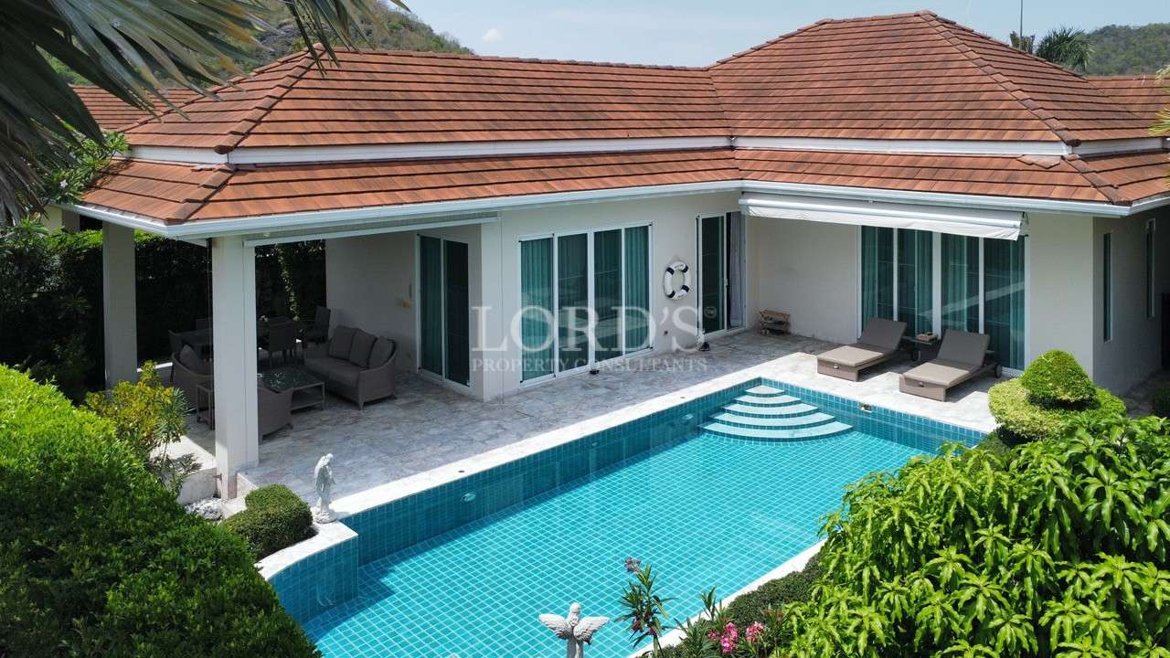 Luxury single-story villa with private swimming pool, patio seating, and tiled roof