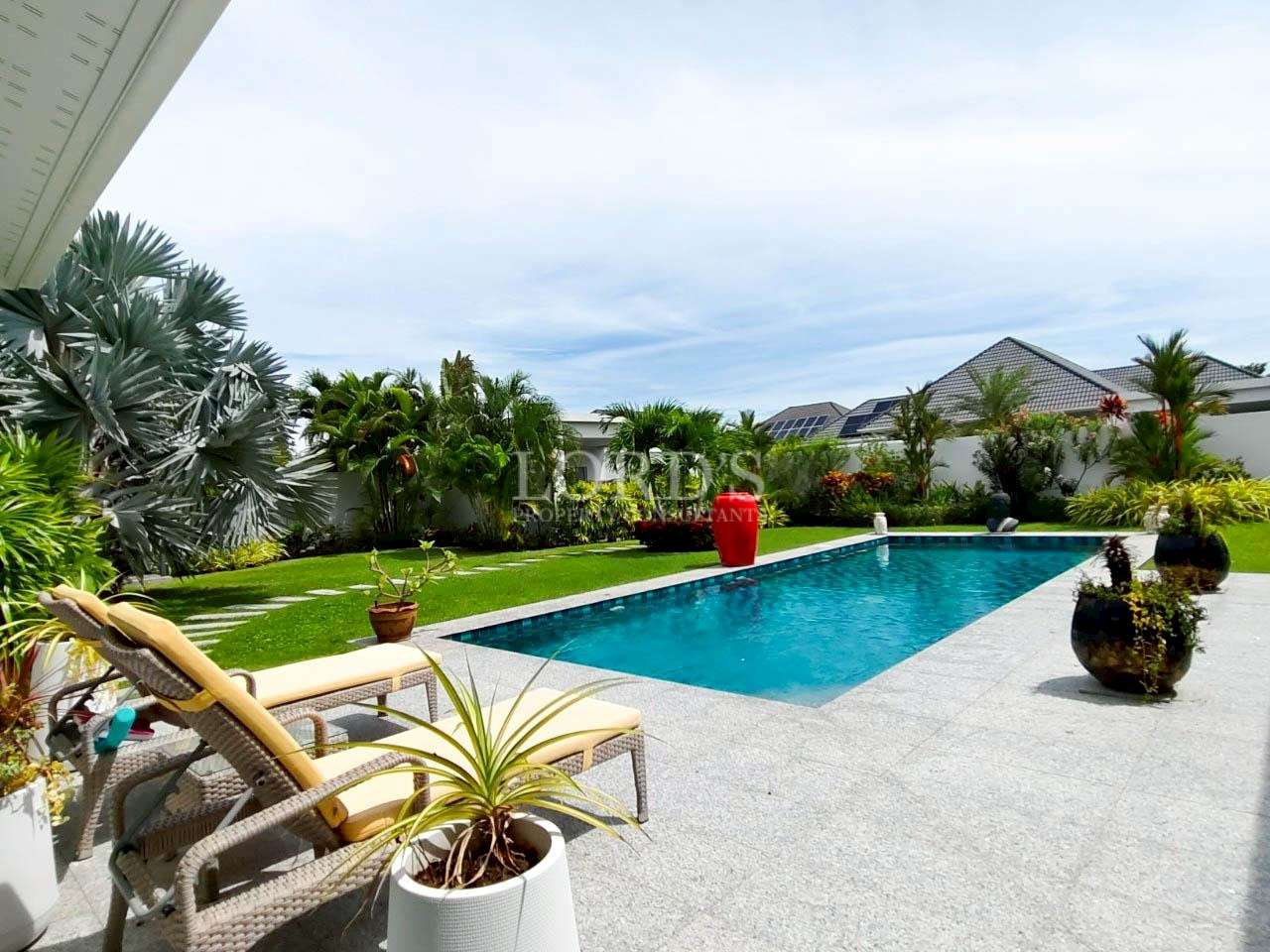 Luxurious poolside garden with greenery.