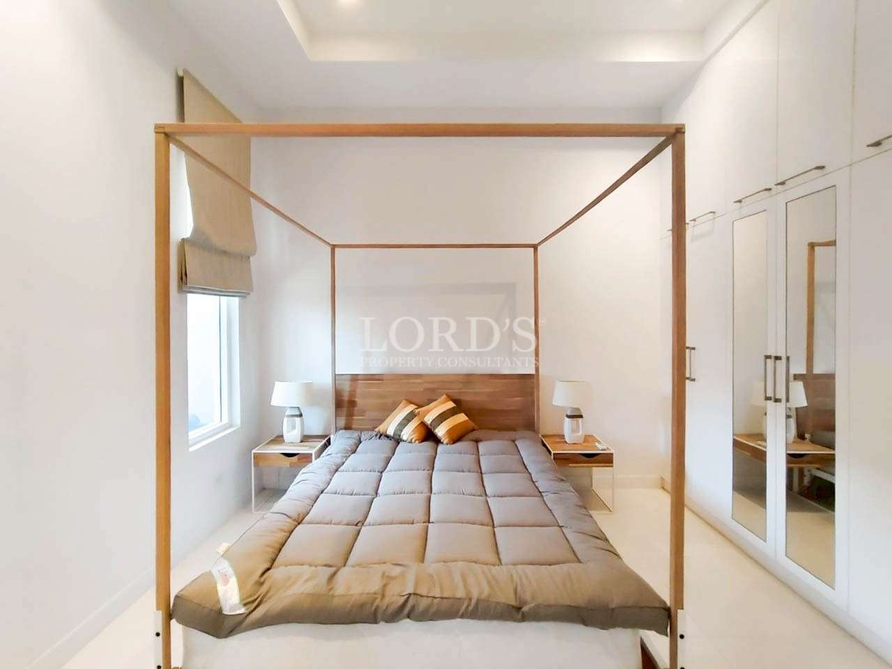 Minimalist bedroom with wooden four-poster bed, bedside tables, and white wardrobe