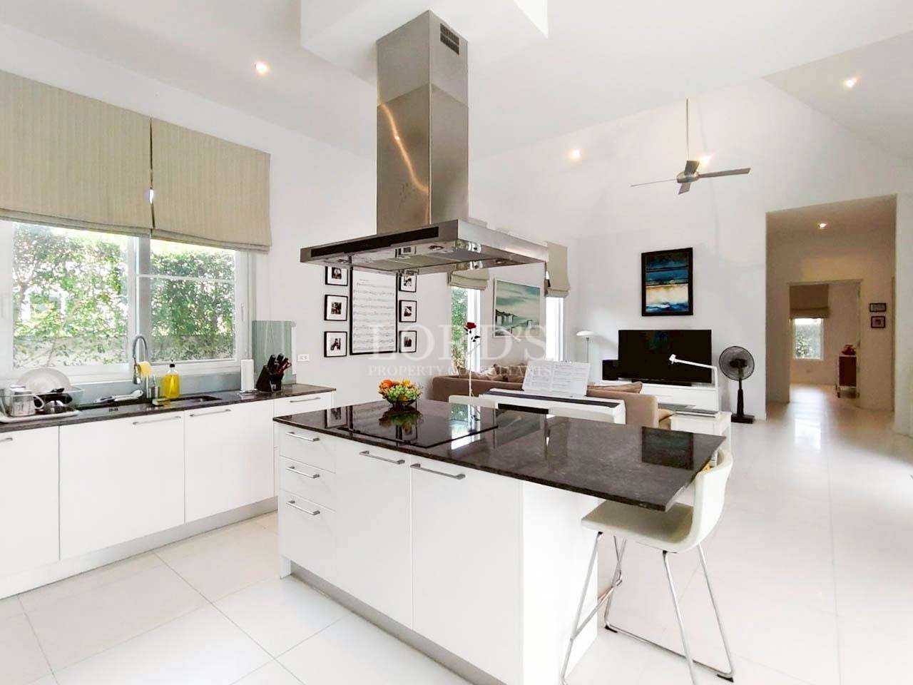 Modern open kitchen with white cabinets, black island countertop, and stainless steel range hood