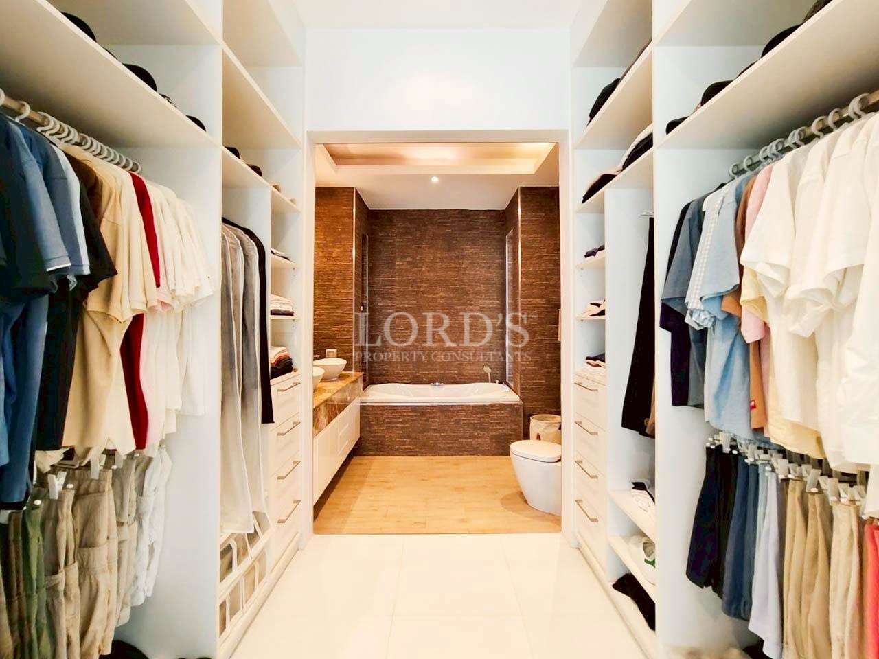 Luxury walk-in closet with built-in shelving, hanging clothes, and direct bathroom access